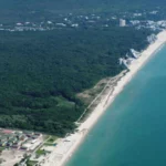 The nude beach is located shortly after crossing the small river between resorts