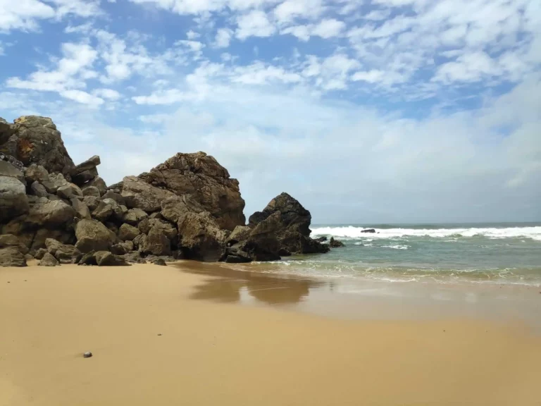 Interesting rock formations among soft sand at Praia do Abano